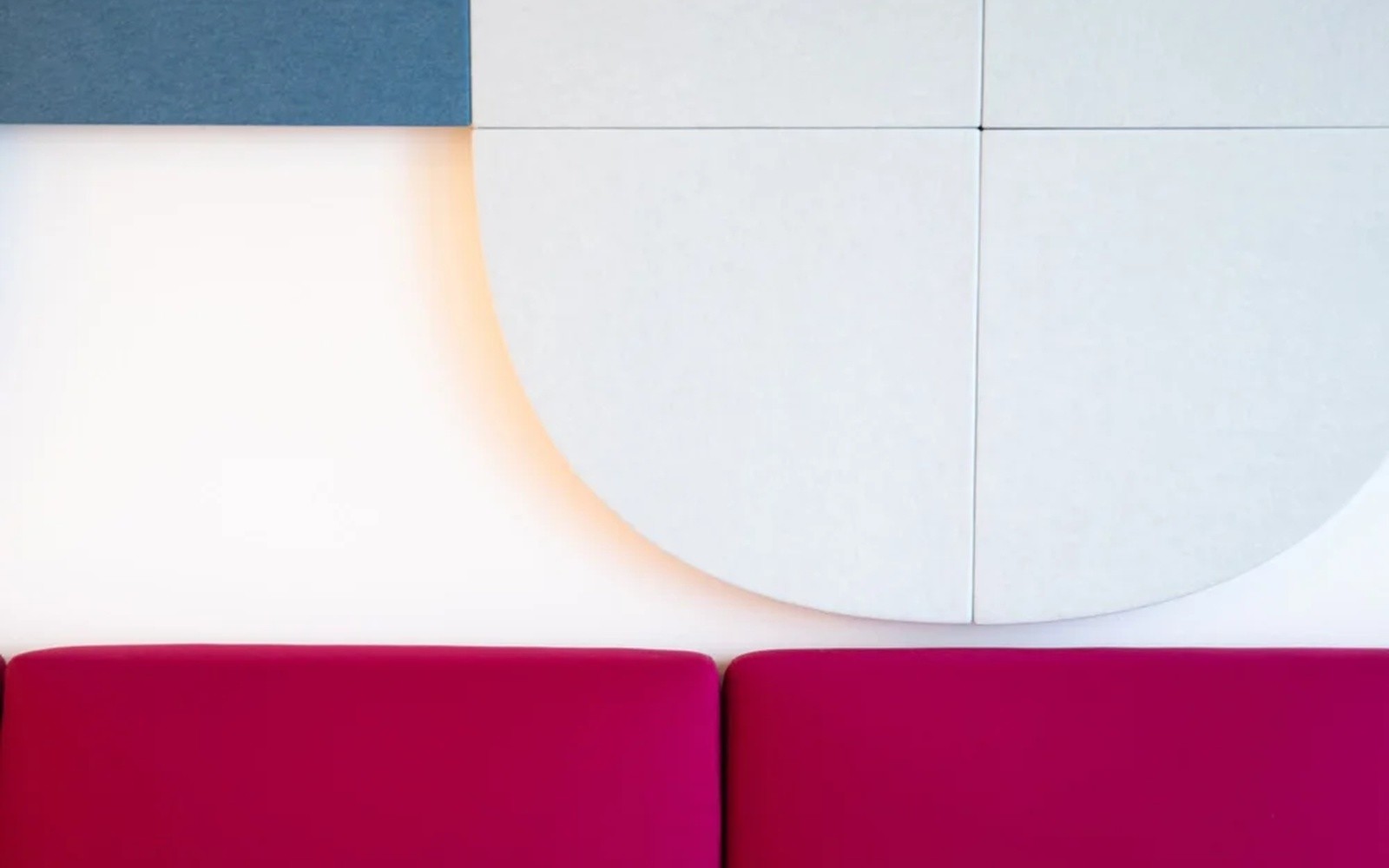Detailaufnahme einer roten Sitzbank vor geometrischen Akustikpaneelen