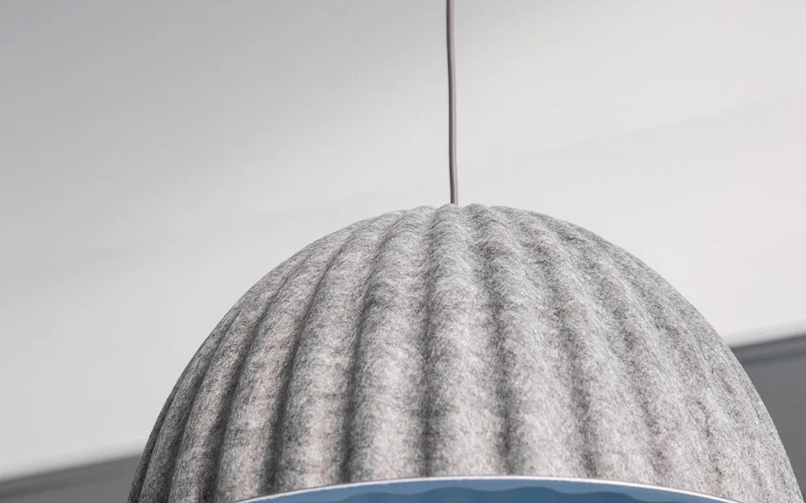 Detailaufnahme einer grauen textilen Pendelleuchte in einem modernen Arbeitsbereich
