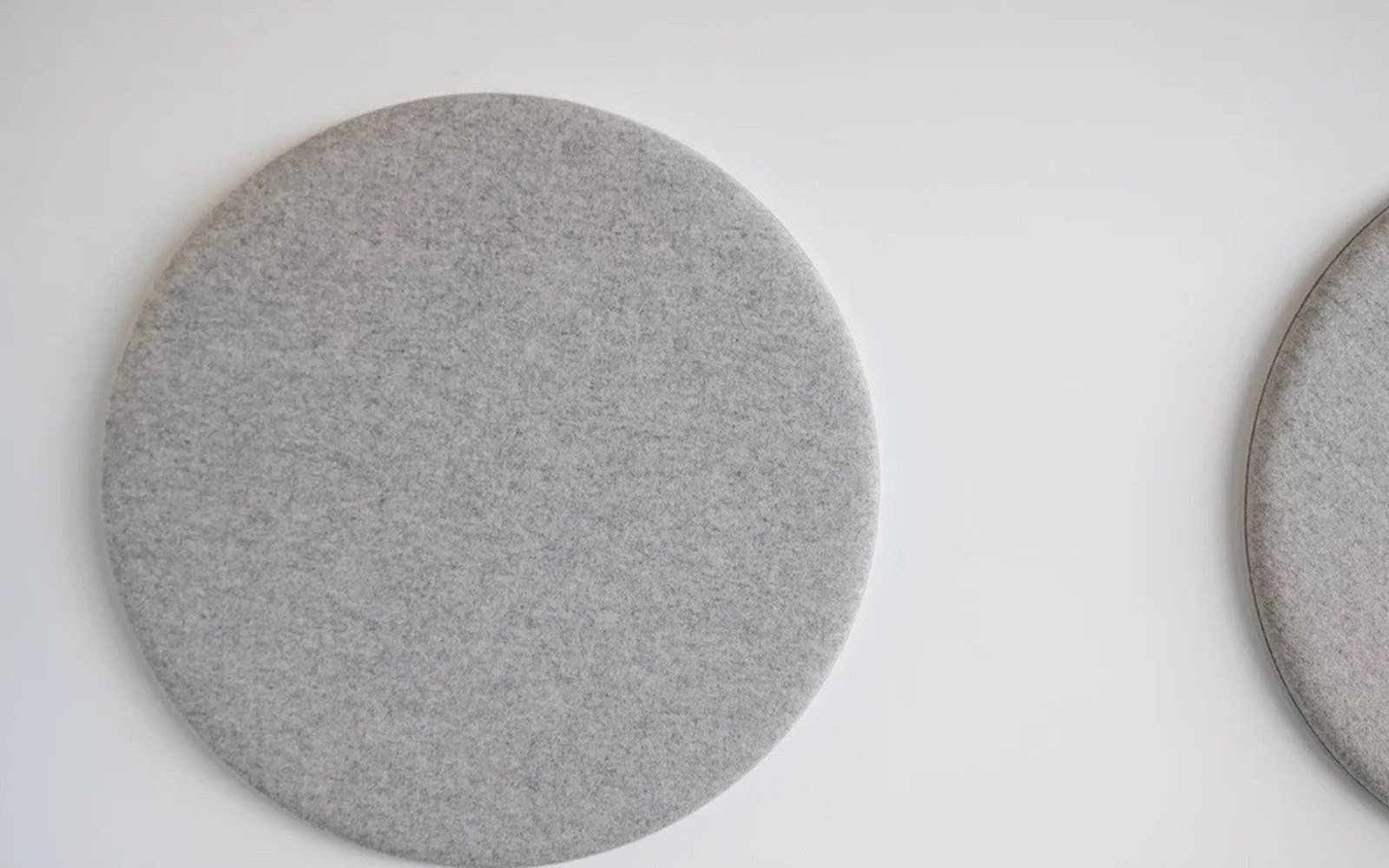 Runde graue Akustikelemente an einer hellen Wand